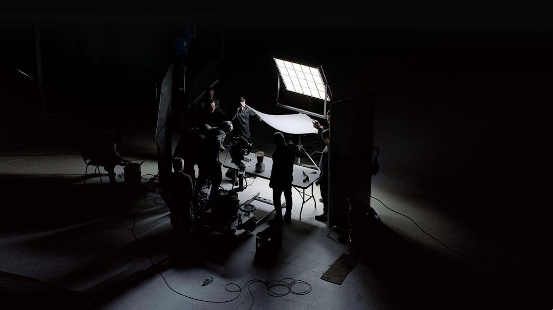 Équipe en tournage dans un studio sombre, éclairée par des panneaux